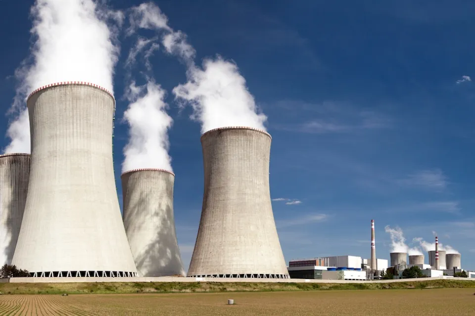 Nuclear power plant with four massive towers emitting white vapor.